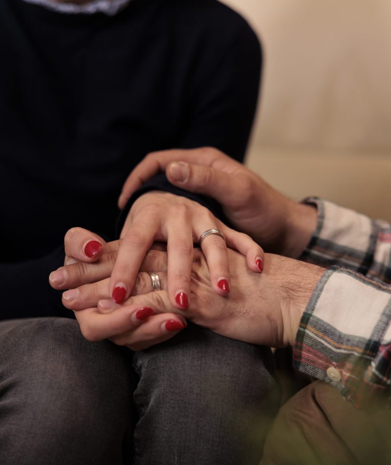 Life partners holding hands at couple therapy session with counseling specialist, enjoying reconciliation after marriage issues. Solving relationship problems with professional help. Close up.